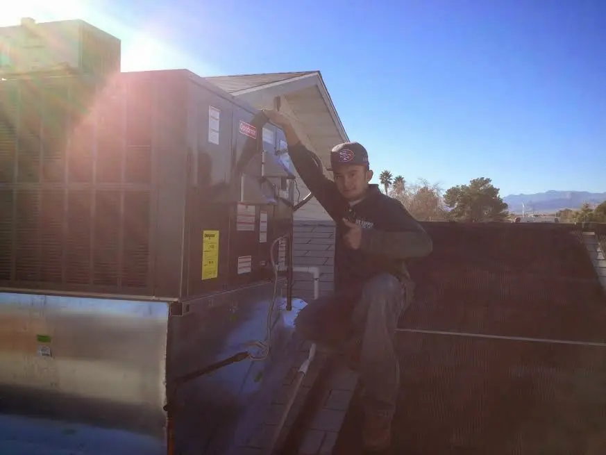 HVAC technician performing Air Duct Cleaning on a rooftop unit in Candler-McAfee